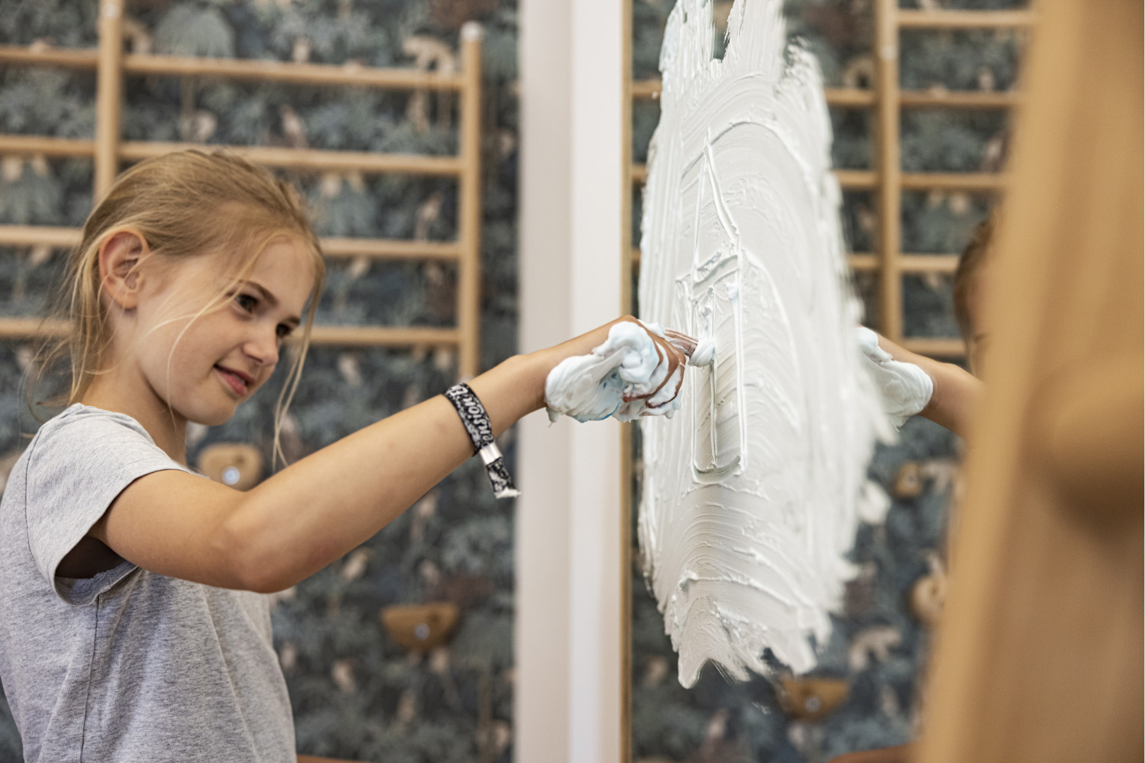 Ein Kind malt mit Schaum an einem Spiegel