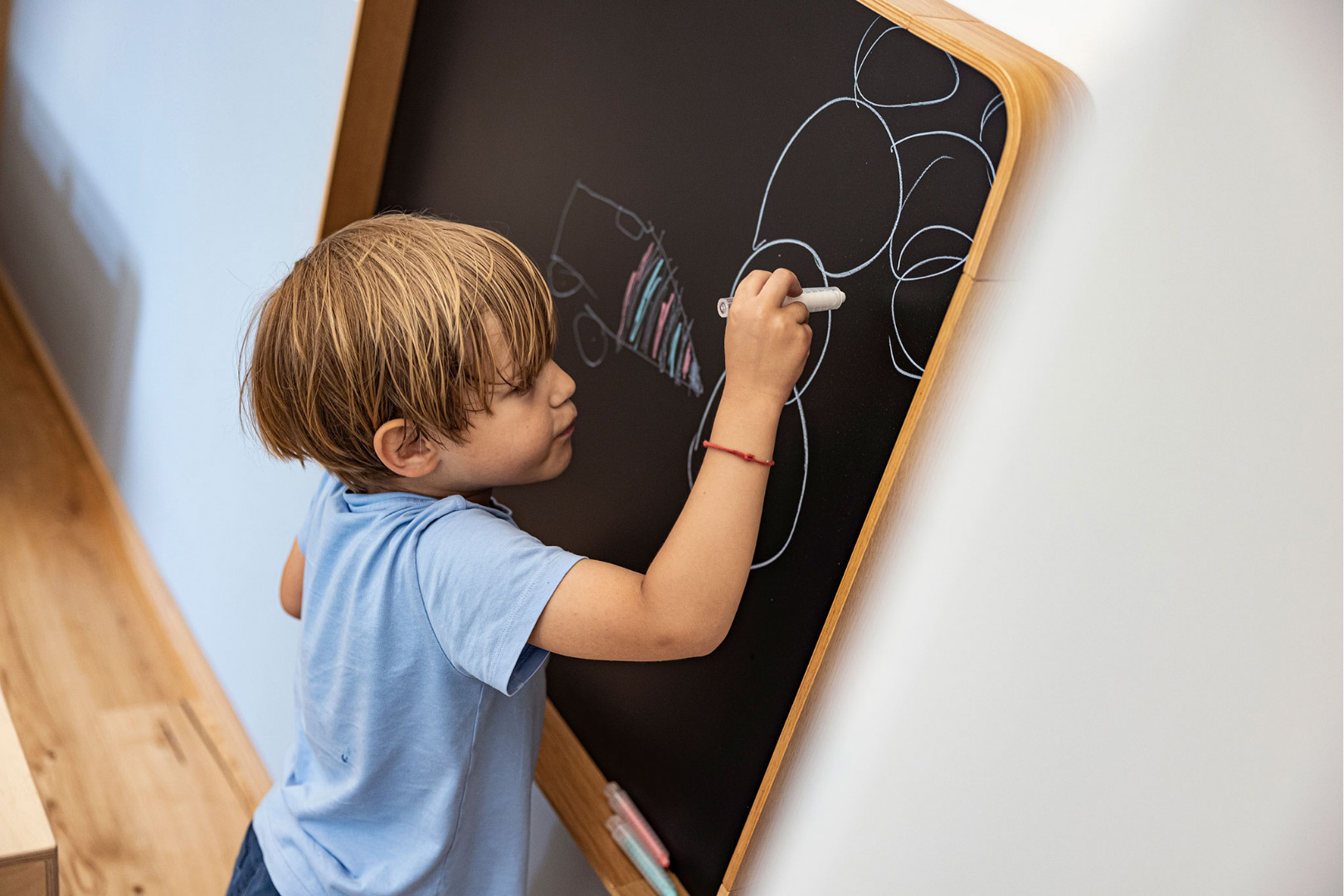 Ein Kind malt an einer Tafel mit bunten Kreiden